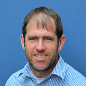 Smiling man with brown hair in blue striped shirt